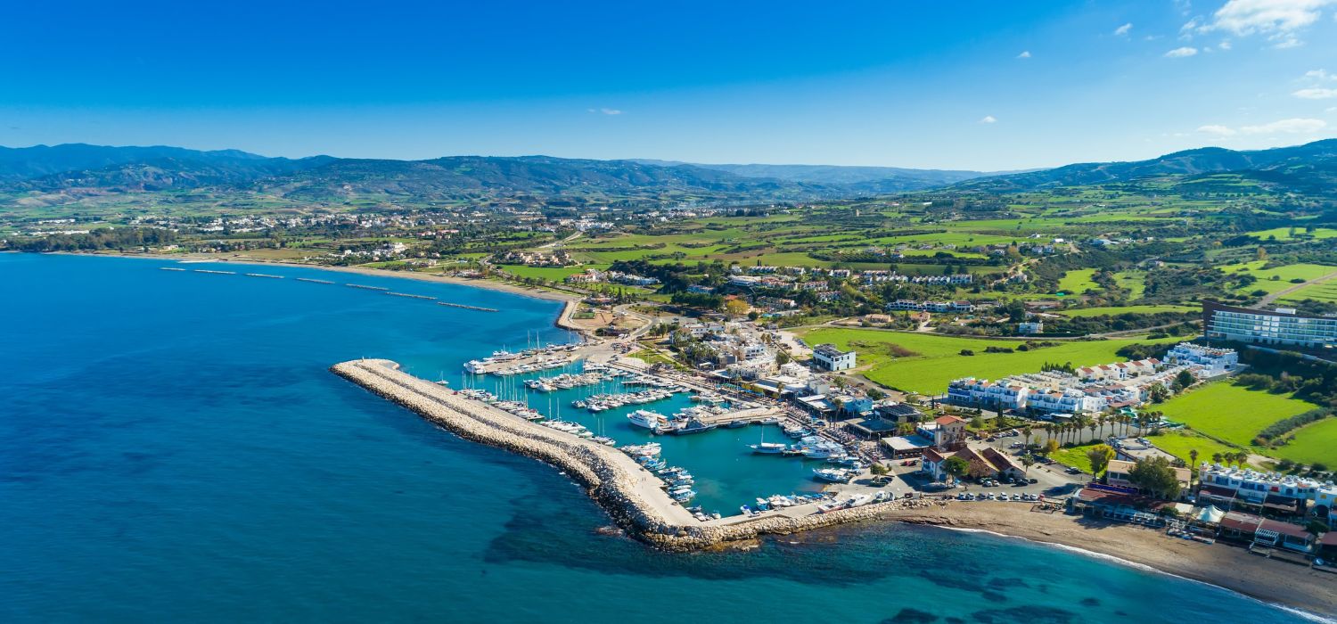 Aerial bird's eye view of Latchi port, Akamas peninsula, Polis Chrysochous, Paphos, Cyprus. The Latsi harbour with boats and yachts, fish restaurants, a promenade, beach tourist area and mountains from above.