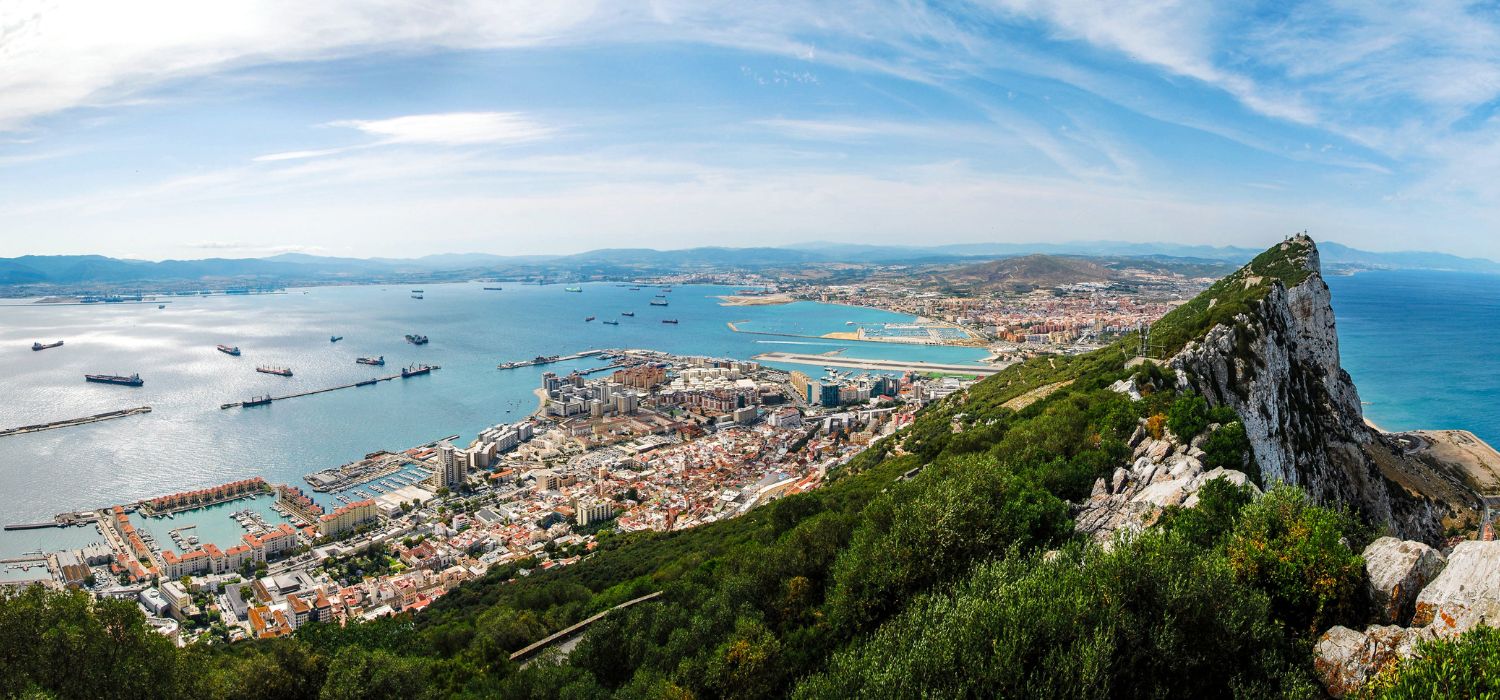 Gibraltar Rock view from above, on the left Gibraltar town and bay, La Linea town in Spain at the far end, Mediterranean Sea on the right