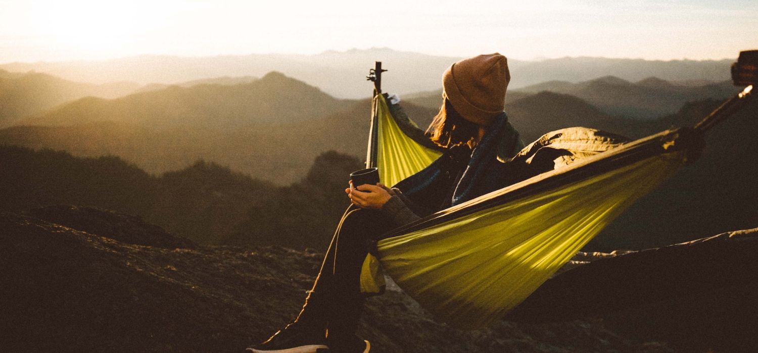 Unrecognizable woman sitting in hammock above mountains